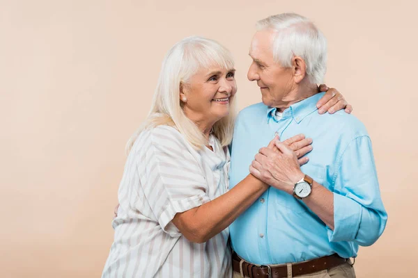 Feliz jubilado mujer mirando alegre senior hombre aislado en beige — Stock Photo