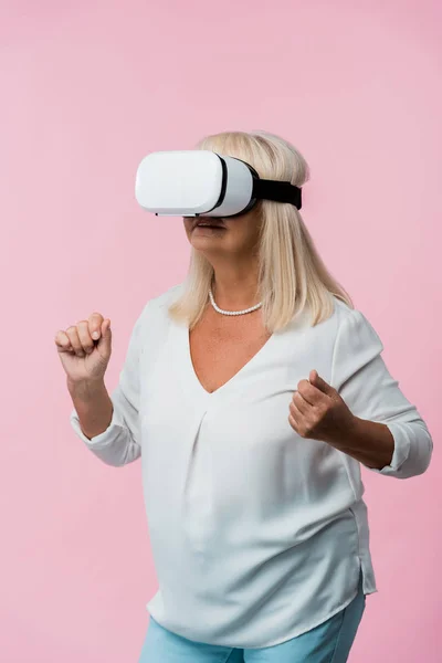 Femme âgée portant casque de réalité virtuelle et geste isolé sur rose — Photo de stock