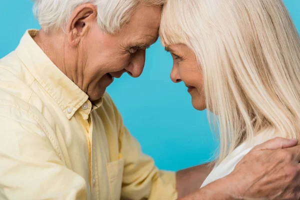 Happy retired couple looking at each other and smiling on blue — Stock Photo