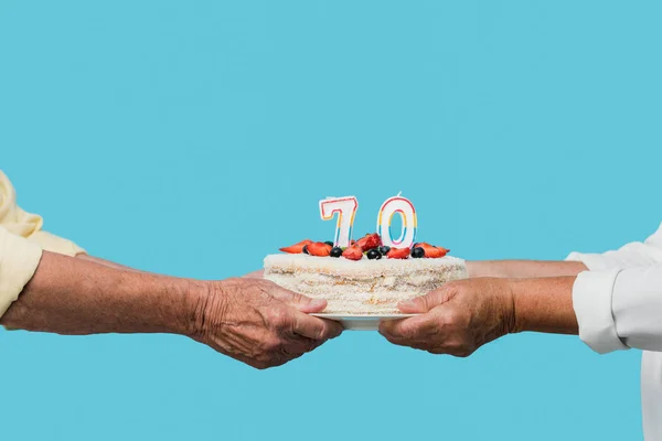 Cropped view of retired couple holding tasty birthday cake isolated on blue — Stock Photo