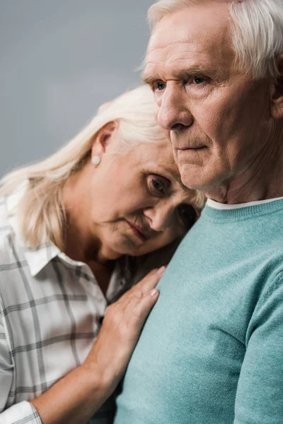 Сумний чоловік на пенсії біля розчарованої старшої дружини, дивлячись на камеру ізольовано на сірому — стокове фото