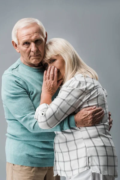 Trauriger Rentner umarmt frustrierte Seniorin und bedeckt Gesicht isoliert auf grau — Stockfoto