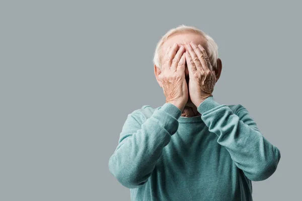 Senior Mann mit grauen Haaren bedeckt Gesicht mit Händen isoliert auf grau — Stockfoto