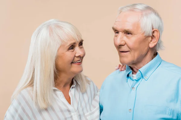 Happy retired woman looking at man with grey hair isolated on beige — Stock Photo