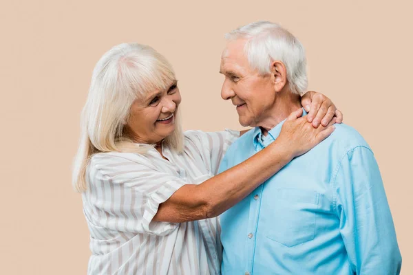 Mujer jubilada feliz abrazando marido mayor aislado en beige - foto de stock