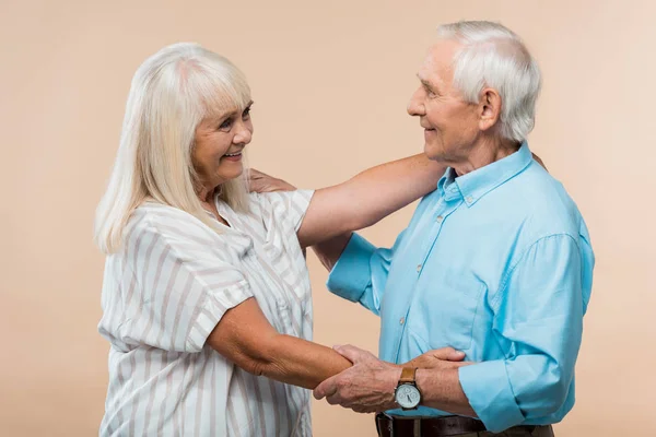 Senior woman smiling while looking at pensioner isolated on beige — Stock Photo