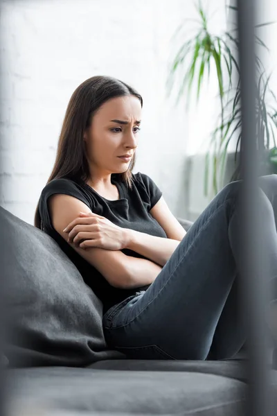 Foco seletivo de chorar jovem mulher sentada no sofá e sofrendo de depressão — Fotografia de Stock