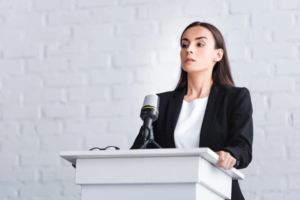 Pretty young lecturer suffering from fear of public speaking while standing on podium tribune — Stock Photo