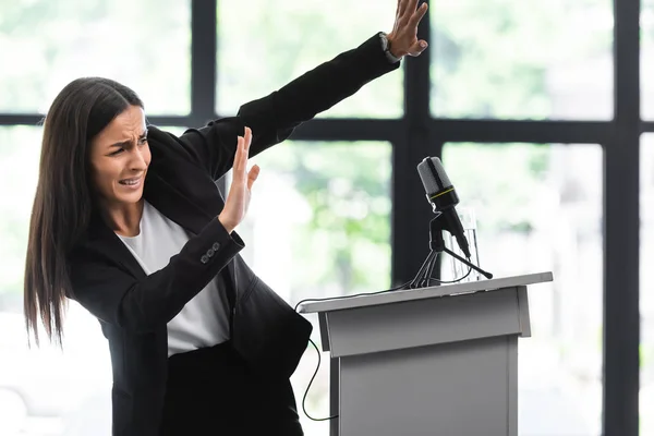 Verängstigter Dozent, der unter Angst leidet, öffentlich mit den Händen gestikulierend auf der Podiumstribüne im Konferenzsaal zu stehen — Stockfoto