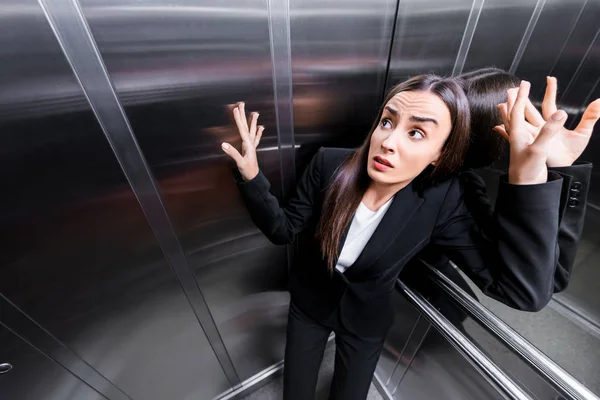 Young scared businesswoman suffering from claustrophobia in elevator — Stock Photo