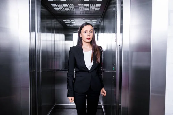 Молодая бизнесвумен, страдающая клаустрофобией, стоящая в лифте и смотрящая в камеру — стоковое фото