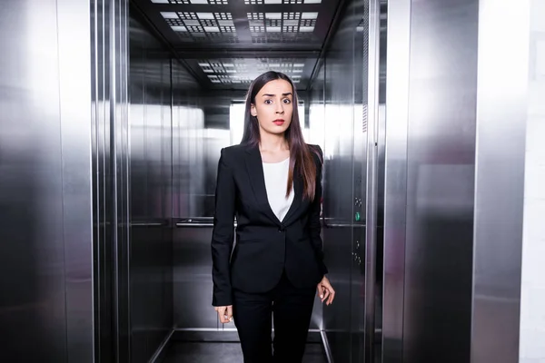 Joven empresaria, con claustrofobia, parada en ascensor y mirando a la cámara - foto de stock