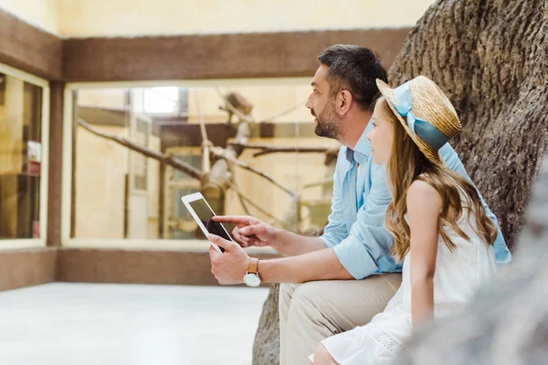 Enfoque selectivo del hombre guapo sosteniendo tableta digital cerca de niño en sombrero de paja - foto de stock