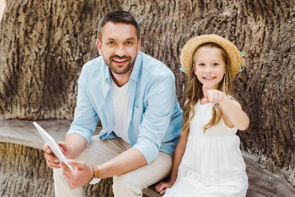 Вибірковий фокус щасливої дитини, вказуючи пальцем біля батька з цифровим планшетом — стокове фото