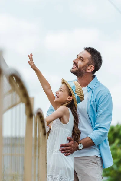 Cheerful kid gesturing standing standing with happy man — Stock Photo