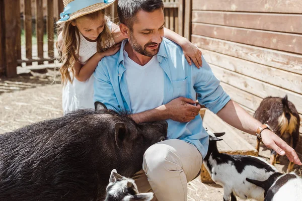 Fröhlicher Mann berührt Ziege neben süßer Tochter und Wildschwein im Zoo — Stockfoto