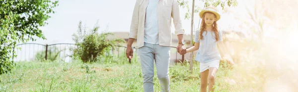 Panoramic shot of father and daughter walking near green plants and holding hands — Stock Photo