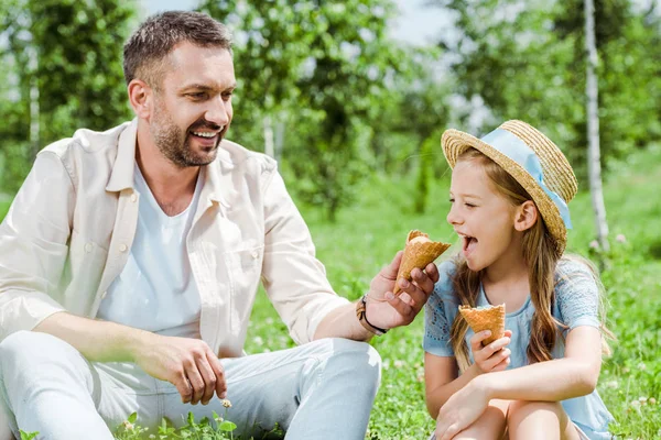 Enfant gai avec bouche ouverte près du cône de crème glacée et père heureux — Photo de stock