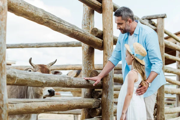 Selective focus of father and kid standing near wooden fence with bison in zoo — Stock Photo