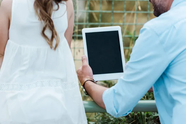 Vista recortada del niño cerca del padre sosteniendo tableta digital en el zoológico - foto de stock