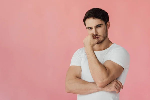 Serious pensive muscular man in white t-shirt looking at camera isolated on pink — Stock Photo