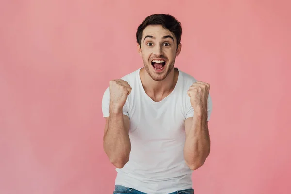 Vista frontal del hombre musculoso excitado en camiseta blanca mostrando sí gesto aislado en rosa - foto de stock