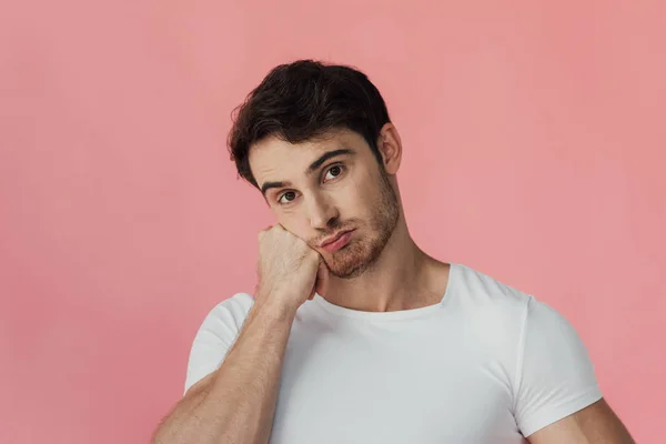 Uomo muscoloso pensoso in t-shirt bianca puntellante pugno crescita viso isolato su rosa — Foto stock