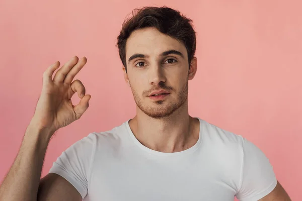 Front view of muscular man in white t-shirt showing okay sign isolated on pink — Stock Photo