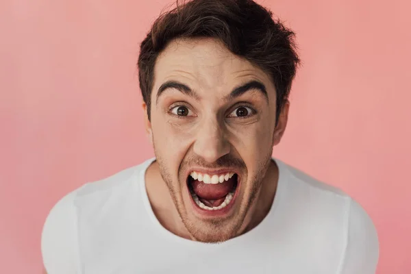 Frontansicht eines wütenden Mannes, der schreit und isoliert auf rosa Kamera schaut — Stockfoto