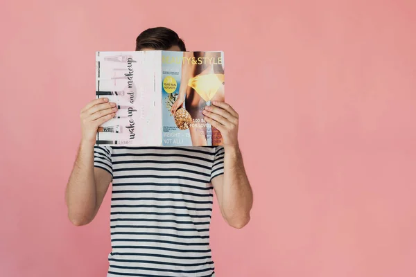 Front view of man in striped t-shirt reading magazine isolated on pink — Stock Photo