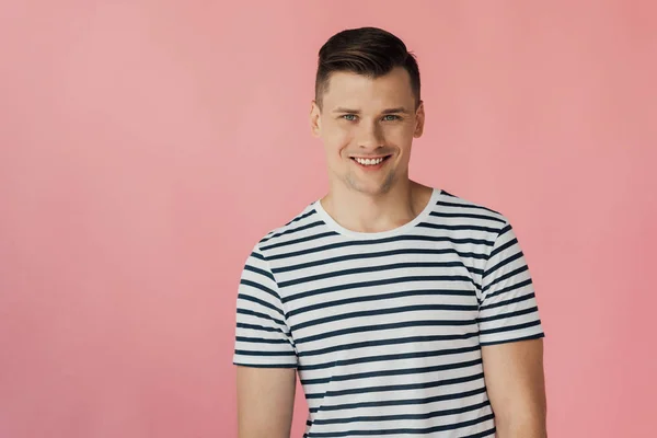 Vorderseite eines gut aussehenden lächelnden Mannes im gestreiften T-Shirt, der isoliert in die Kamera auf rosa schaut — Stockfoto