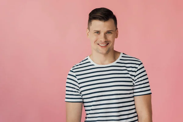 Vue de face du bel homme souriant en t-shirt rayé regardant la caméra isolée sur rose — Photo de stock