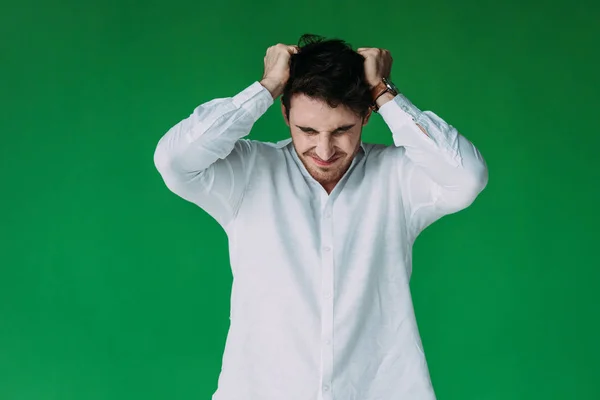 Front view of stressed man in white shirt touching hair isolated on green — Stock Photo