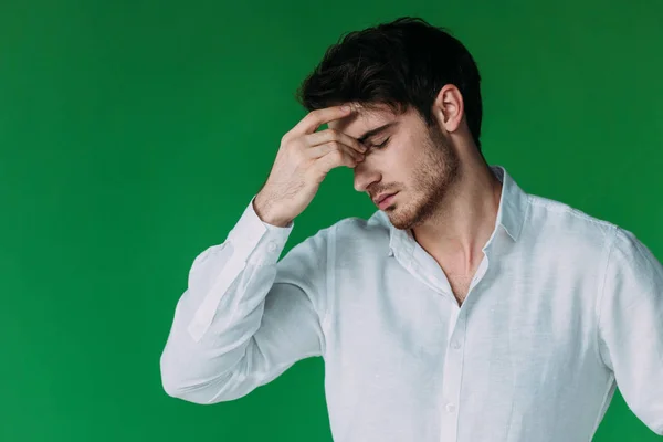 Tired man in white shirt touching face with closed eyes isolated on green — Stock Photo