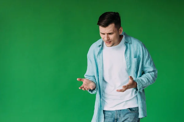 Joven irritado en camisa gesto aislado en verde - foto de stock