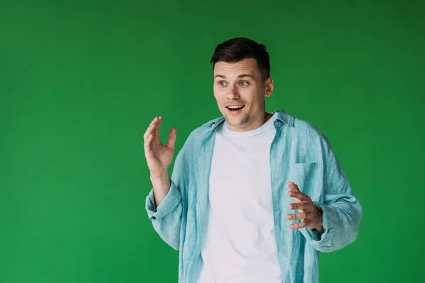 Eccitato giovane uomo in camicia gesticolando isolato sul verde — Foto stock