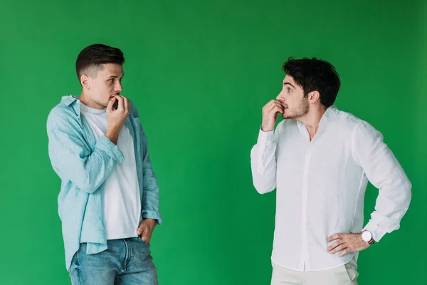 Deux hommes inquiets mordant des doigts et se regardant isolés sur vert — Photo de stock