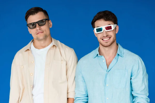 Vista frontal de dos amigos sonrientes en gafas 3D aisladas en azul - foto de stock
