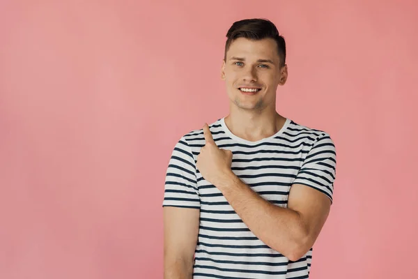 Vista frontal do jovem sorridente em t-shirt listrada olhando para a câmera isolada em rosa — Fotografia de Stock