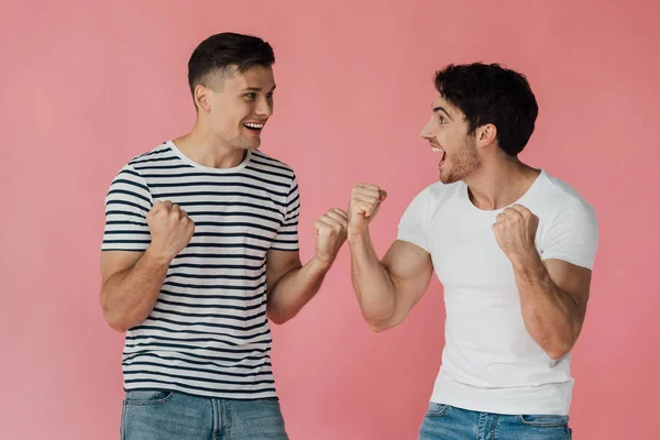 Двоє збуджених друзів у футболках дивляться один на одного і показують так жести ізольовані на рожевому — стокове фото