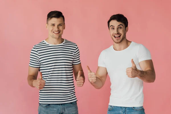 Frontansicht zweier aufgeregter Freunde in T-Shirts, die vereinzelt Daumen nach oben auf rosa zeigen — Stockfoto