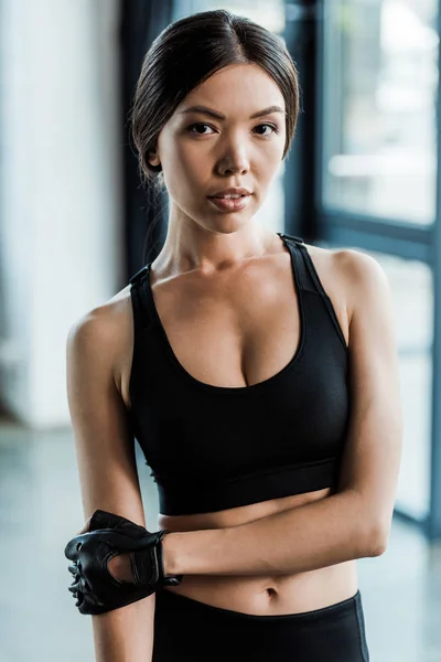 Femme attrayante en vêtements de sport regardant la caméra dans la salle de gym — Photo de stock