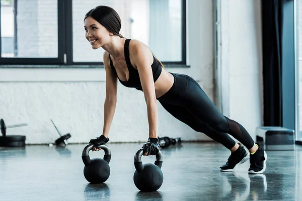 Mujer alegre en ropa deportiva haciendo ejercicio con pesas - foto de stock
