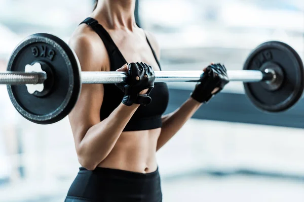 Cropped view of young woman in sportswear exercising with barbell in gym — Stock Photo