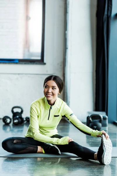 Fröhliche junge Frau in Sportbekleidung beim Stretching im Fitnessstudio — Stockfoto