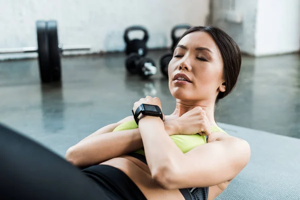 Attractive young woman with closed eyes doing do abs on fitness mat — Stock Photo