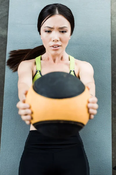 Foco seletivo de menina segurando bola enquanto deitado no tapete de fitness — Fotografia de Stock