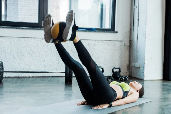 Glückliche junge Frau trainiert mit Ball auf Fitnessmatte im Fitnessstudio — Stockfoto