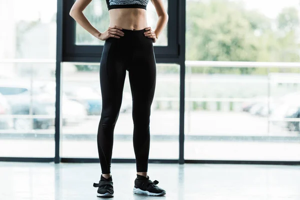 Cropped view of sportswoman standing with hands on hips — Stock Photo