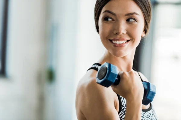 Fille heureuse et sportive faisant de l'exercice avec haltère dans le centre sportif — Photo de stock